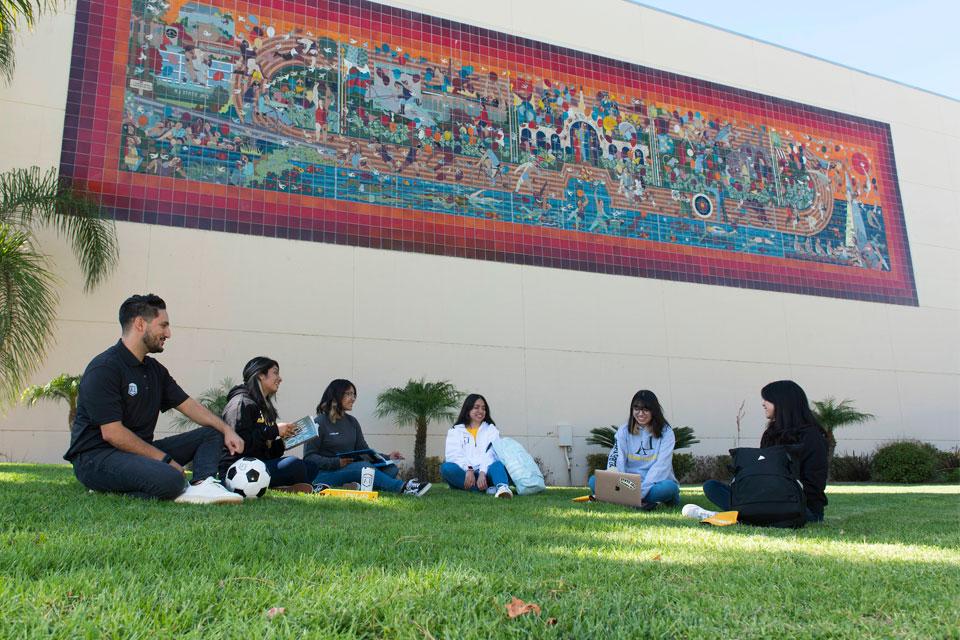 足彩外围网站的学生在大学体育大楼附近的校园里闲逛.